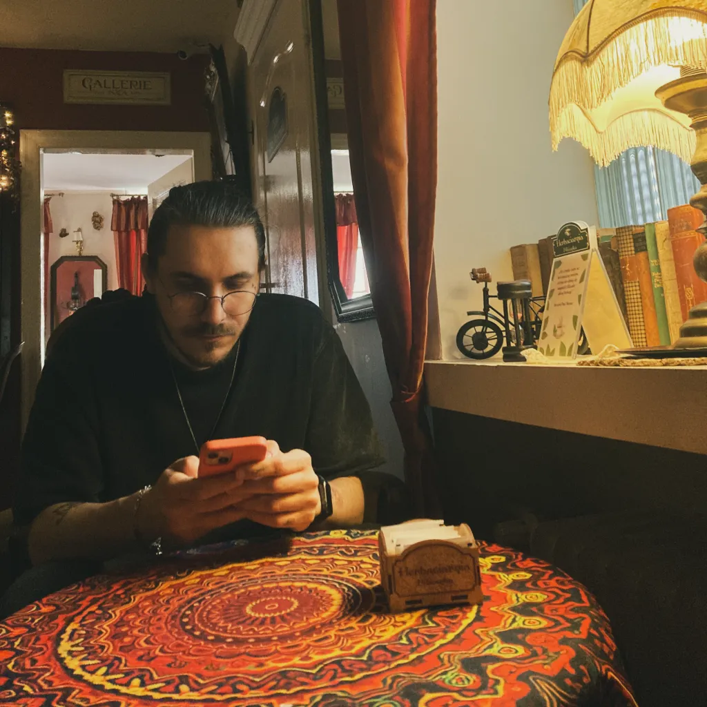 Damian Cholewa, author of Game Compendium, on his phone at a table with vintage stuff around